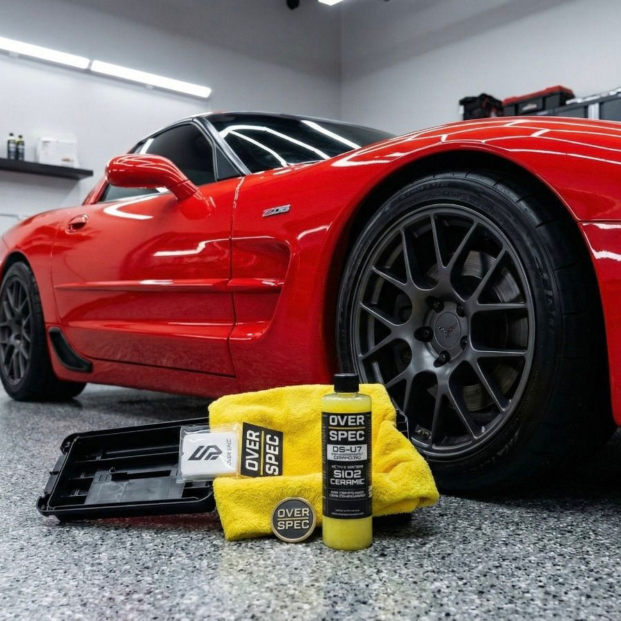 Red sports car with car care products on a garage floor